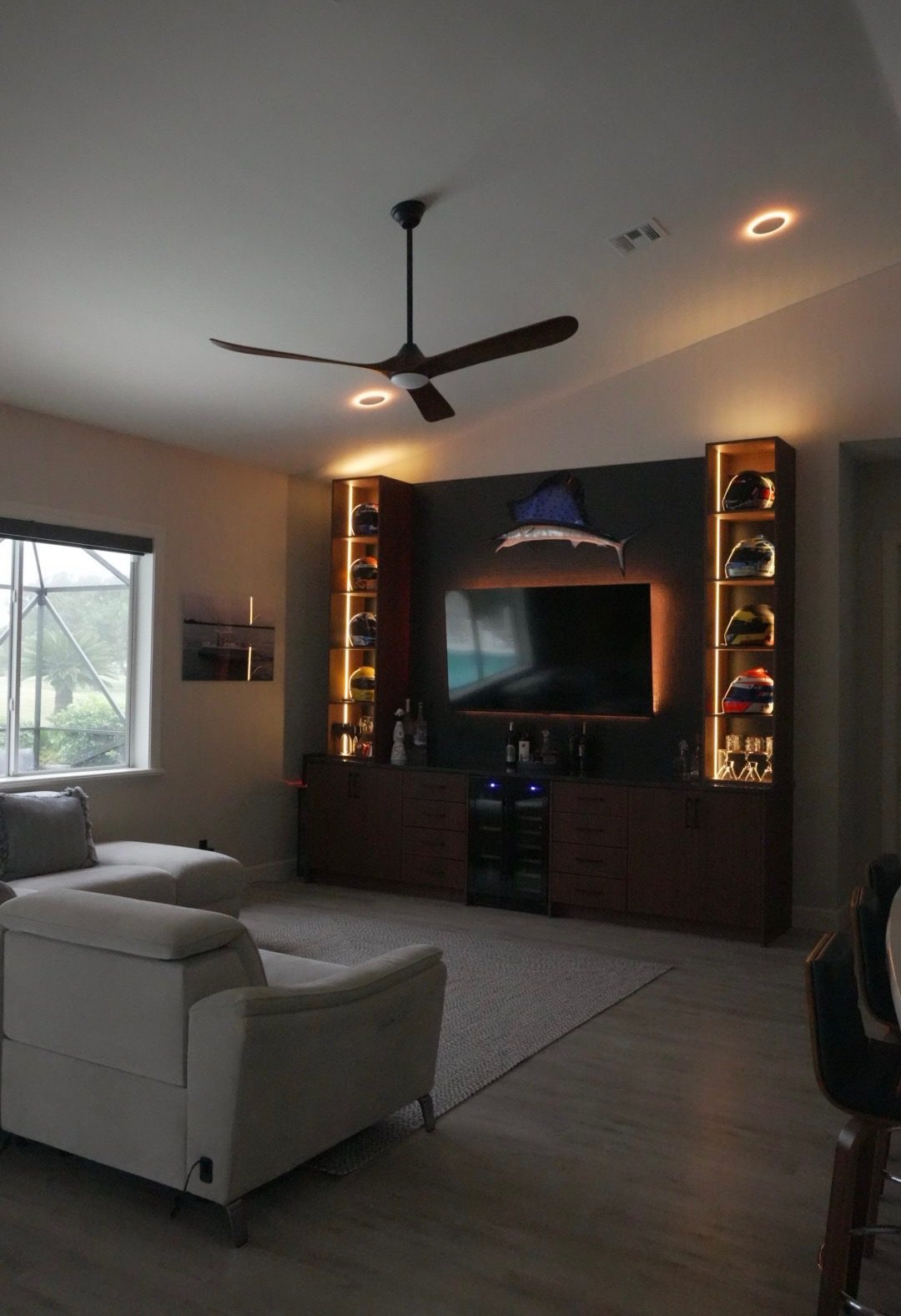 Custom built-in cabinetry with lit display shelves and a backlit TV wall in a Vero Beach home