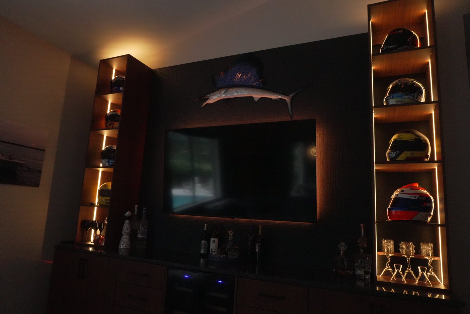 Tall built-in display shelves with integrated LED strip lighting beside a mounted TV