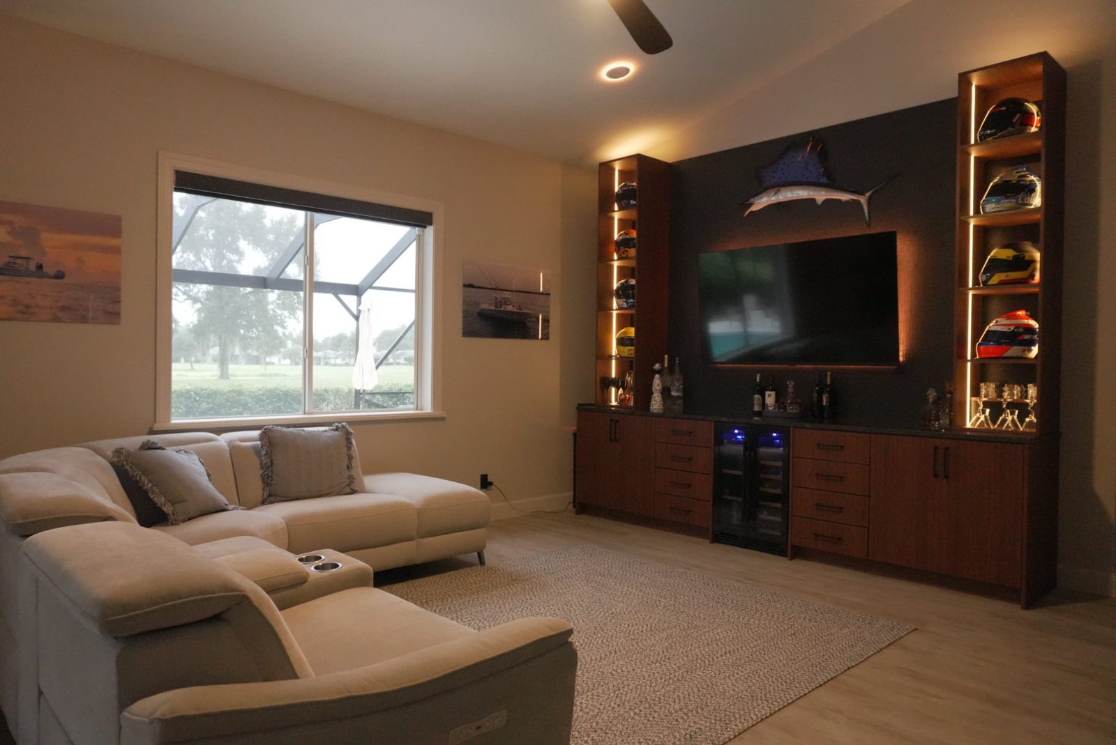Finished built-in media wall with beverage cooler, lit shelving and a sectional sofa in a Florida living room