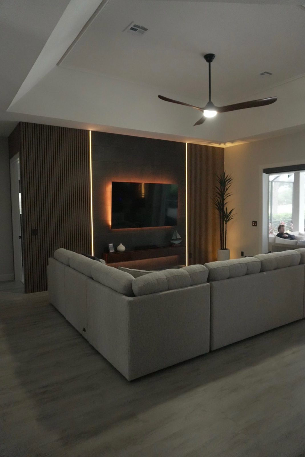Slat accent wall with recessed ceiling lights and a ceiling fan in a custom living room media wall