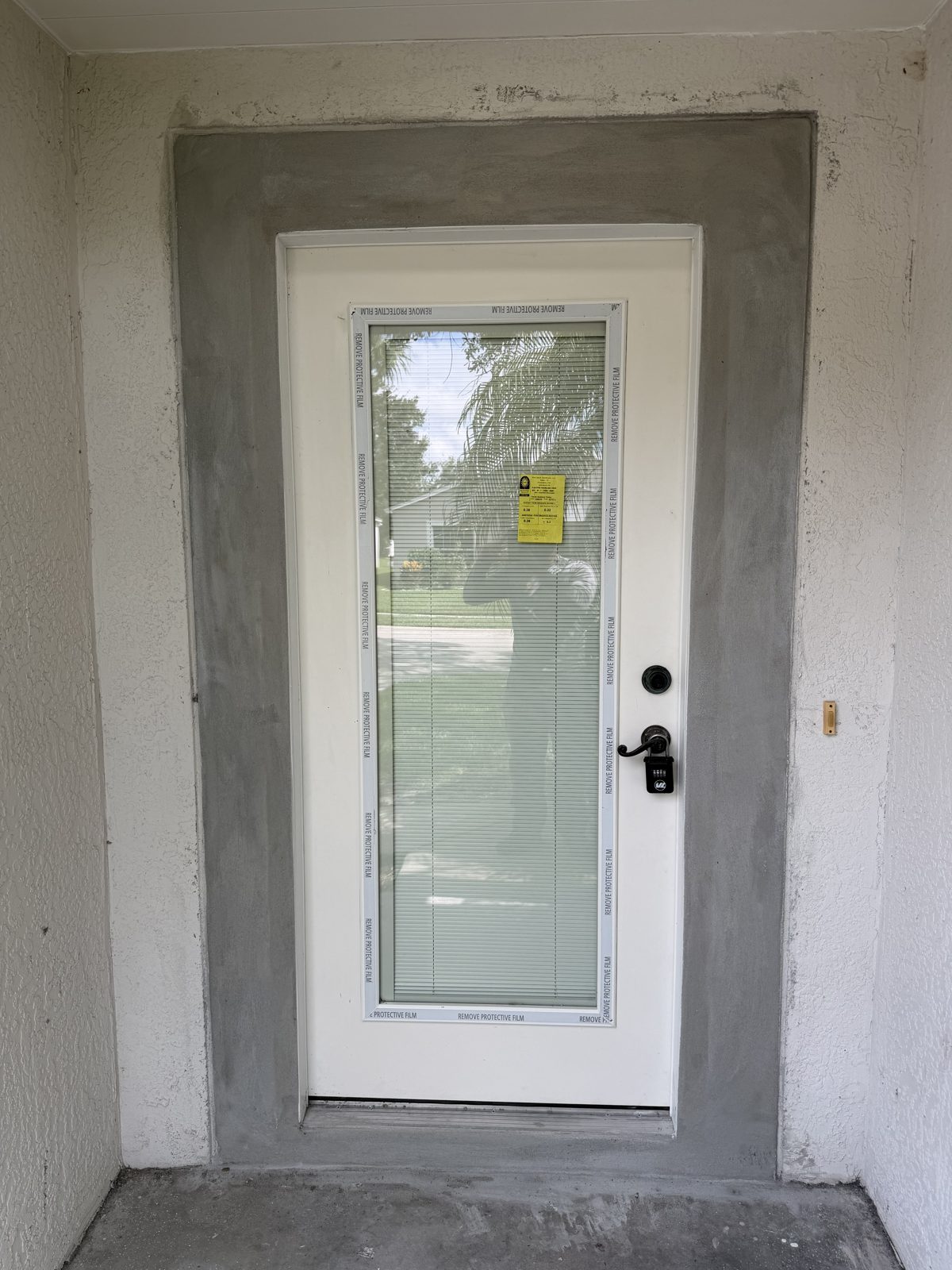 New white entry door with a half-glass panel installed in a stucco opening with a fresh stucco patch around the frame